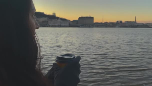 Señora bebiendo café caliente cerca del río en la ciudad por la noche — Vídeo de stock