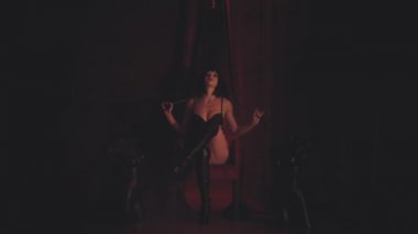 Siyahlı kadın kırmızı koltukta oturuyor.