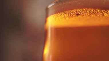 Beer with bubbles and foam in glass. Closeup.