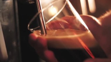 Bartender pours dark beer into a glass