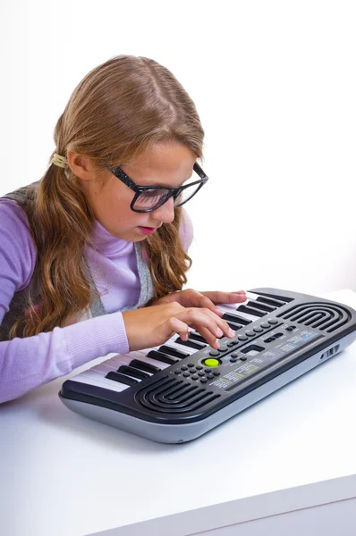 Schoolmeisje spelen op een kleine synthesizer — Stockfoto