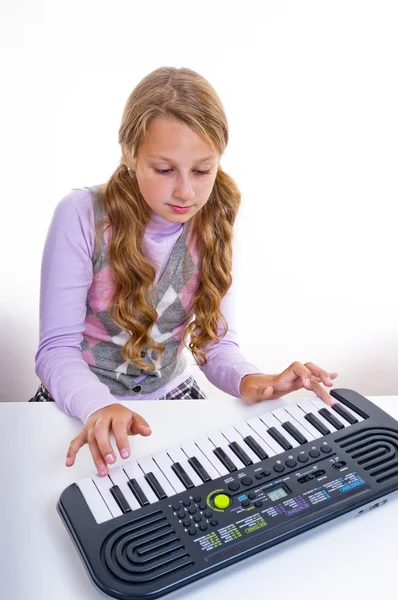 Schulmädchen spielt auf einem kleinen Synthesizer — Stockfoto