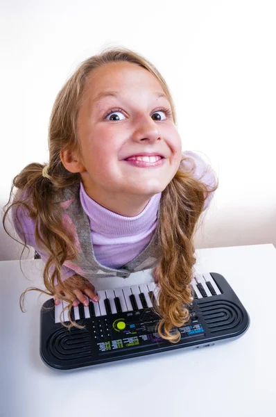 Schulmädchen spielt auf einem kleinen Synthesizer — Stockfoto