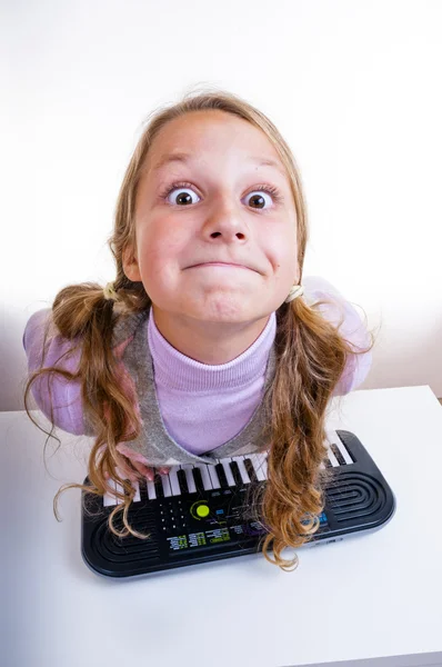 Colegiala jugando en un pequeño sintetizador — Foto de Stock