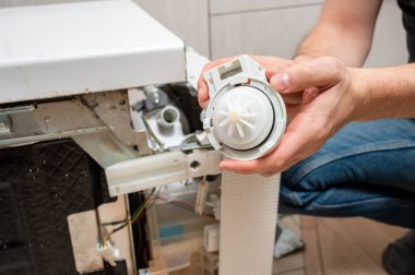 Yıkanmış bir bulaşıkçının arka planına karşı bir adamın ellerinde bulaşık makinesi için yeni bir pompa.