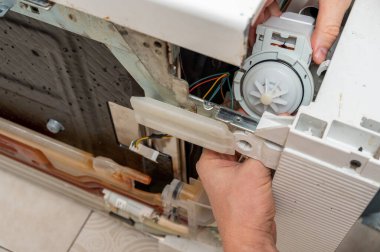 Adam yeni pompayı bulaşık makinesine sokuyor.