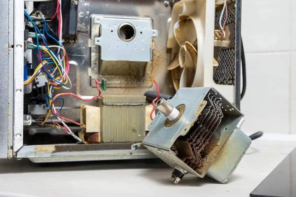 拆卸的微波炉旁边的旧磁控管 免版税图库照片
