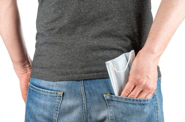 Adam, kotun arka cebinden tıbbi maskeyi çıkar.