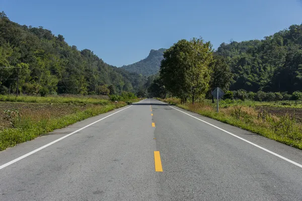 Carretera larga vacía a lo largo de la montaña — Foto de Stock
