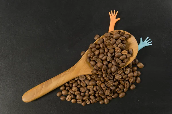 Grain de café en cuillère en bois avec deux mains colorées — Photo