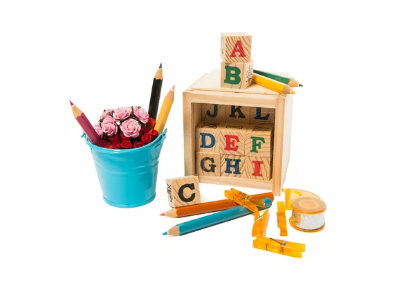 Деревянный алфавитный блок с цветным карандашом, клипами, лентой и голубым ведром цветов — стоковое фото