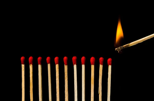 Burning match with row of matches isolated on black background — Stock Photo, Image
