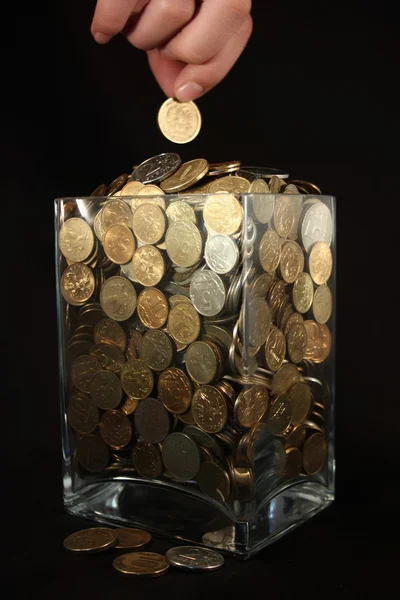 Coins in a glass jar on a black background — Stock Photo, Image