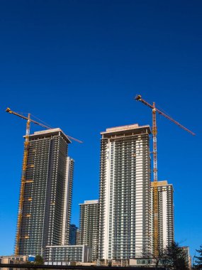 Coquitlam City 'de yeni yüksek binalar, endüstriyel inşaat alanı, inşaat ekipmanları, mavi gökyüzünün arka planında iki inşaat vinci.