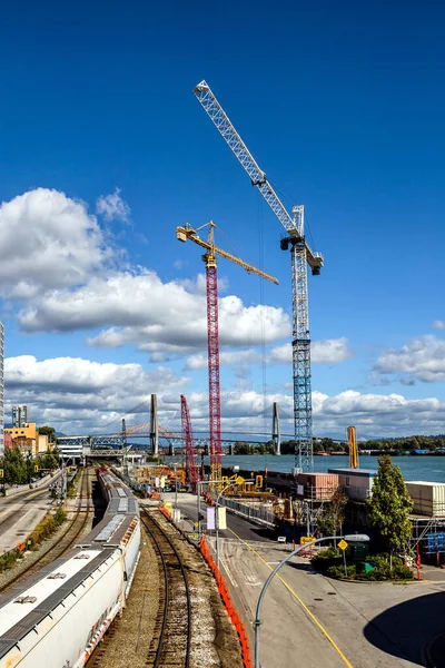 Fraser River 'ın rıhtımı, New Westminster şehir merkezindeki Residential District, nehir kıyısı boyunca inşaat alanı, üç inşaat vinci, yolda trafik. Bahar geldi.