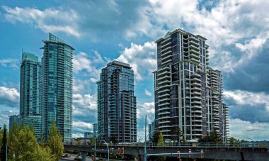 Burnaby City şehir merkezinin mimari parçası, yazın, fırtınalı bulutlu bir gökyüzünün arka planında yeşil ağaçlar