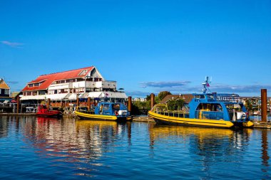 Steveston Village 'daki Marina, Richmond City' nin rıhtımında tatil tekneleri ve restoranların yaz sahaları mavi gökyüzünün arka planında