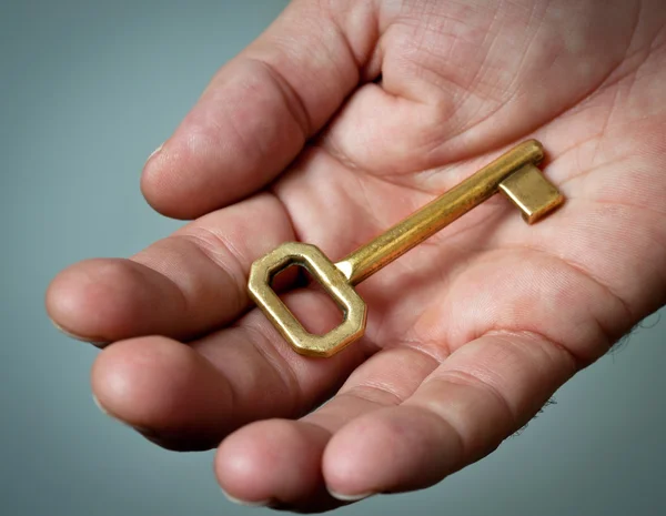 Gouden sleutel in een hand. — Stockfoto