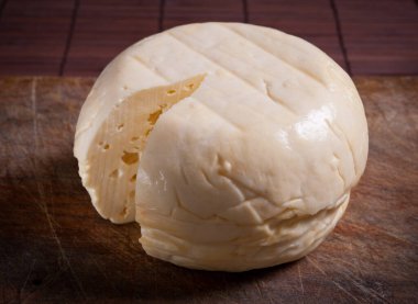 Goat cheese wheel on wooden table.