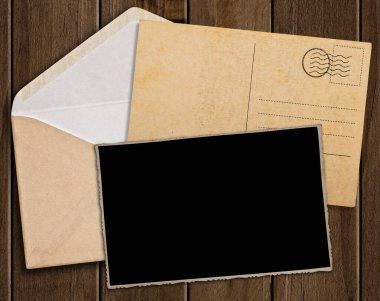 Eski kartpostal, fotoğraf ve ahşap masa üzerinde zarf.