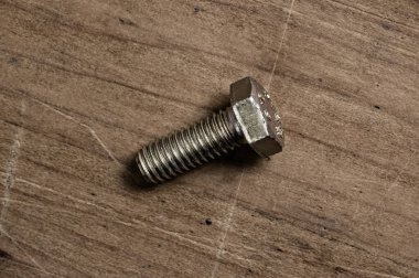 Steel bolt on wooden table.