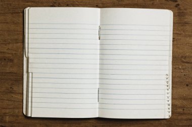 Indexed notebook on wooden table, studio shot.