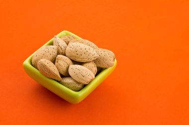 Bir kase badem, turuncu arka plan ile.