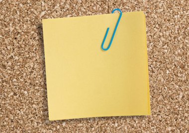 Yellow remainder note isolated on white background, with blue clip.