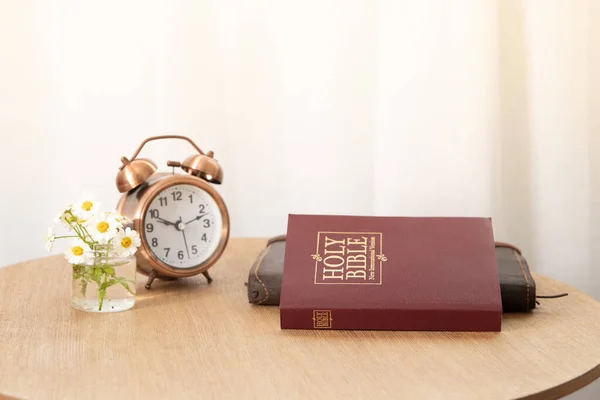 Kutsal İncil ve defter masanın üstünde, pencerenin yanında çalar saat var. İncil kavramını öğrenme zamanı.