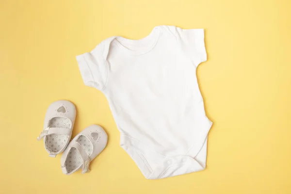 Baby clobodysuit mock-up top view with pumpkins on yellow background for your text or logo place