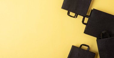 Düz siyah alışveriş torbaları sarı arka planda kara Cuma indiriminde.