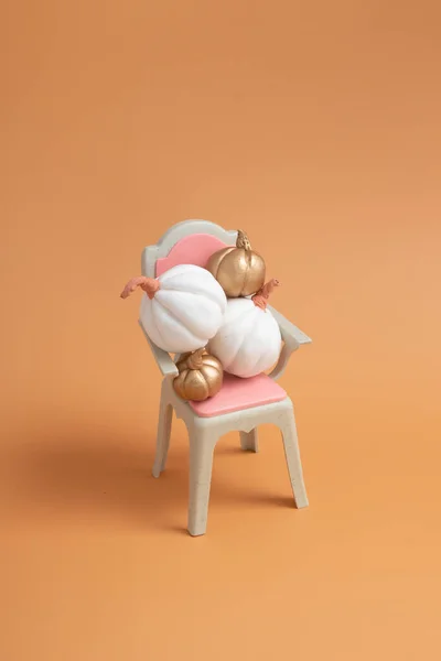 Herbstliches kreatives Stillleben aus weißen und goldenen Kürbissen auf dem Stuhl — Stockfoto
