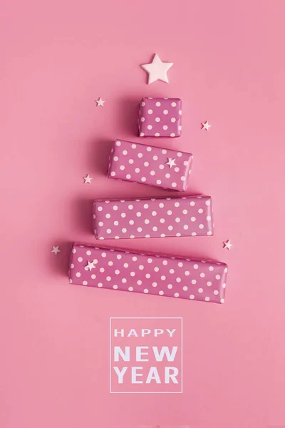 Mutlu yıllar mesajı içeren hediye kutularından yapılmış soyut Noel ağacı içeren yaratıcı bir tebrik kartı.