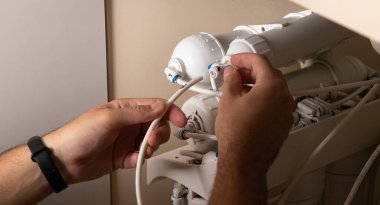 Su filtresini değiştirmek ve yüklemek için bir ustanın elleri