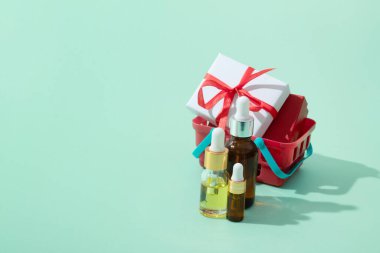 Kozmetik yağ ve serum şişeleri, alışveriş sepetinde pipet ve noel hediyeleri fotokopi alanı.