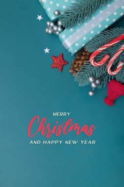Düz hediyeli, böğürtlen ve turkuaz arka planda çam ağacıyla mutlu noel tebrik kartı