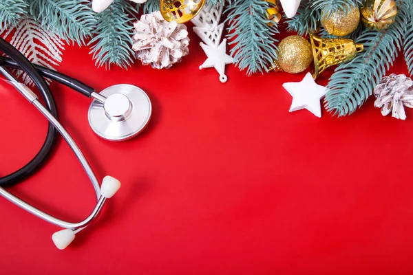 Tıbbi steteskop ve noel süslemeleri kırmızı arka planda ve fotokopi alanında duruyordu. Tıp yılbaşı konsepti