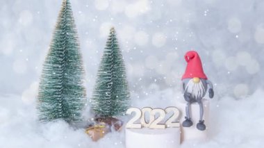 2022 yılının animasyonlu arka planı karlı bir arka planda uçan karla birlikte cüceler ve Noel ağaçları ile