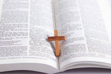 Tahta haçı açık İncil sayfasında kapat