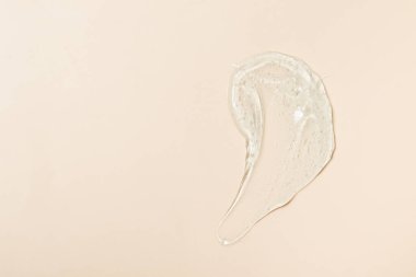 Thick transparent gel, cosmetics soap texture, antiseptic, hyaluron smear on beige top view