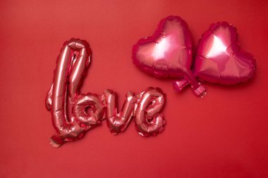 Festive background for Valentine's Day from Foil balloons shape heart and love word on red background