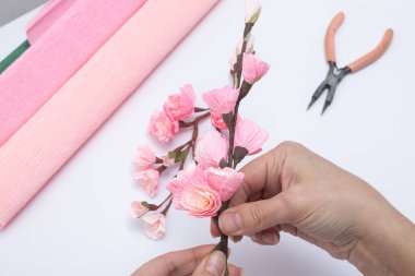 Bükülmüş kağıttan sakura çiçekleri olan bir bahar dalı oluşturuluyor. DIY Master sınıfı.