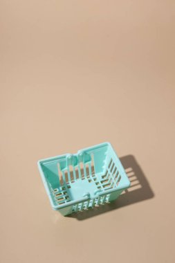 Bej arka planda boş bir alışveriş sepeti. Minimalizm. Satışlar, alışveriş, fiyatlar.