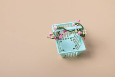 Bej arka planda çiçekler olan boş bir alışveriş sepeti. Minimalizm. Bahar satışları, alışveriş, fiyatlar.