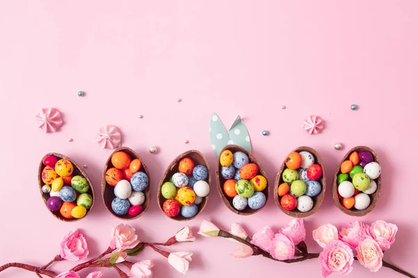 Czekoladowe jajka wielkanocne i wystrój płaski dla dzieci Wielkanoc polowanie jaj koncepcja na różowym tle. Słodycze w kształcie jajka — Zdjęcie stockowe