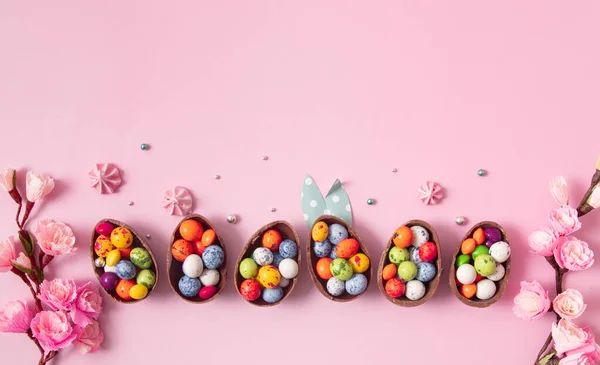 Chocolade paaseieren en decor plat leggen voor kinderen paaseieren jacht concept op roze achtergrond. Snoep in de vorm van een ei — Stockfoto
