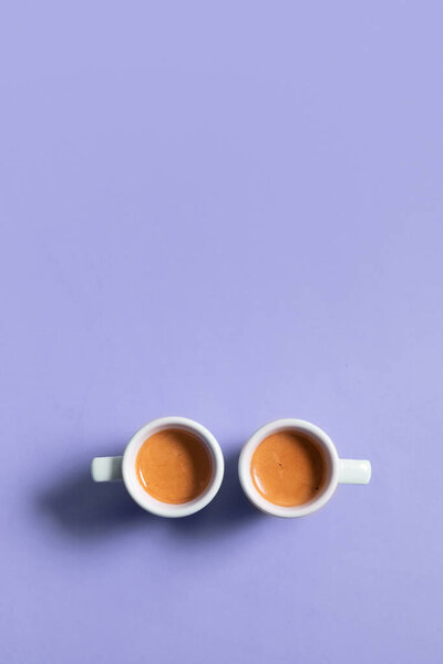 Two ceramic cups of espresso coffee. Top view. Minimalistic vertical stock photo in very peri color.