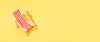 Sarı arka planda pankart plaj koltuğu. Yaz minimalist kavramı.