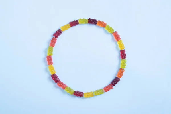 Kreis farbiger Gummibärchen auf pastellblauem Hintergrund. Ansicht von oben — Stockfoto