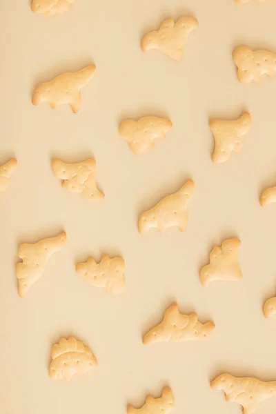 Stock image Cookies pattern in the form of dinosaurs top view on a beige background. Monochrome photo.